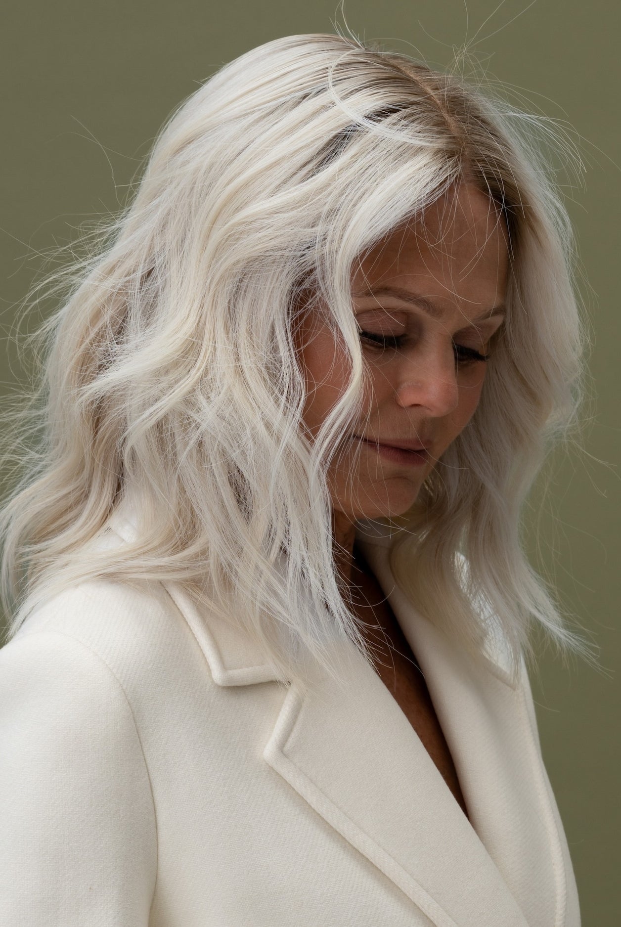 Fiorella Wig 35 cm platinum ash blonde human hair wig with cool dark blonde roots, softly waved and shown on model for a natural look