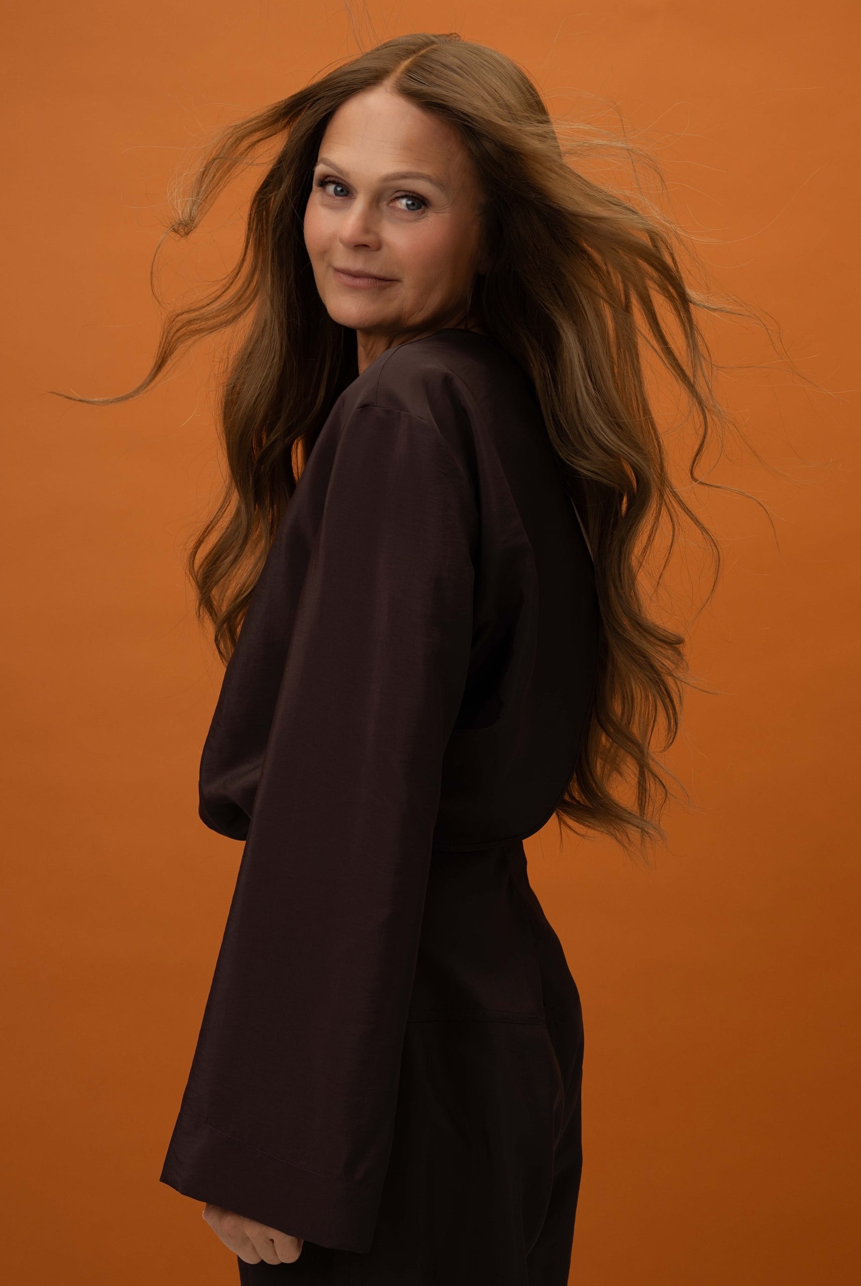 Model side pose with Elena Wig – 50cm full lace wig in caramel brown to medium brown balayage; styled with natural layers.