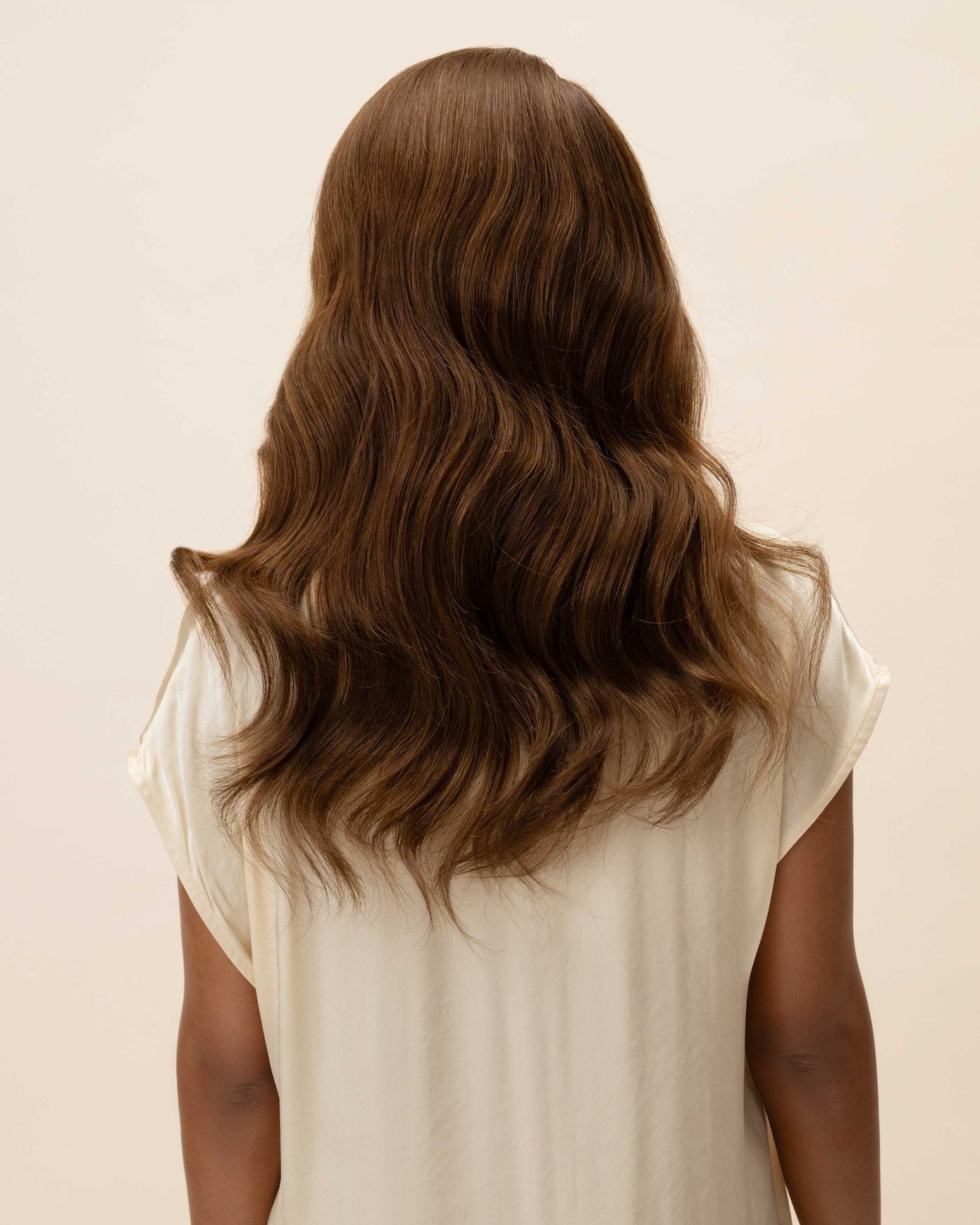 Daisy Wig 40 cm Remy human hair wig in dark brown with subtle light brown highlights, softly layered and shown from the back on model.