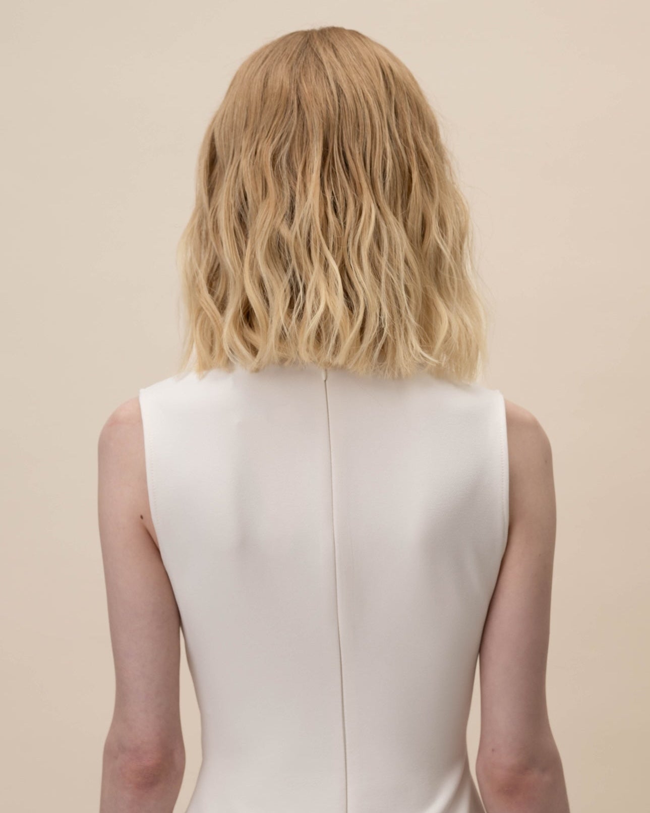 Statice Wig 30 cm Remy human hair wig in medium blonde with soft golden tones and natural darker root, shown from the back on model.