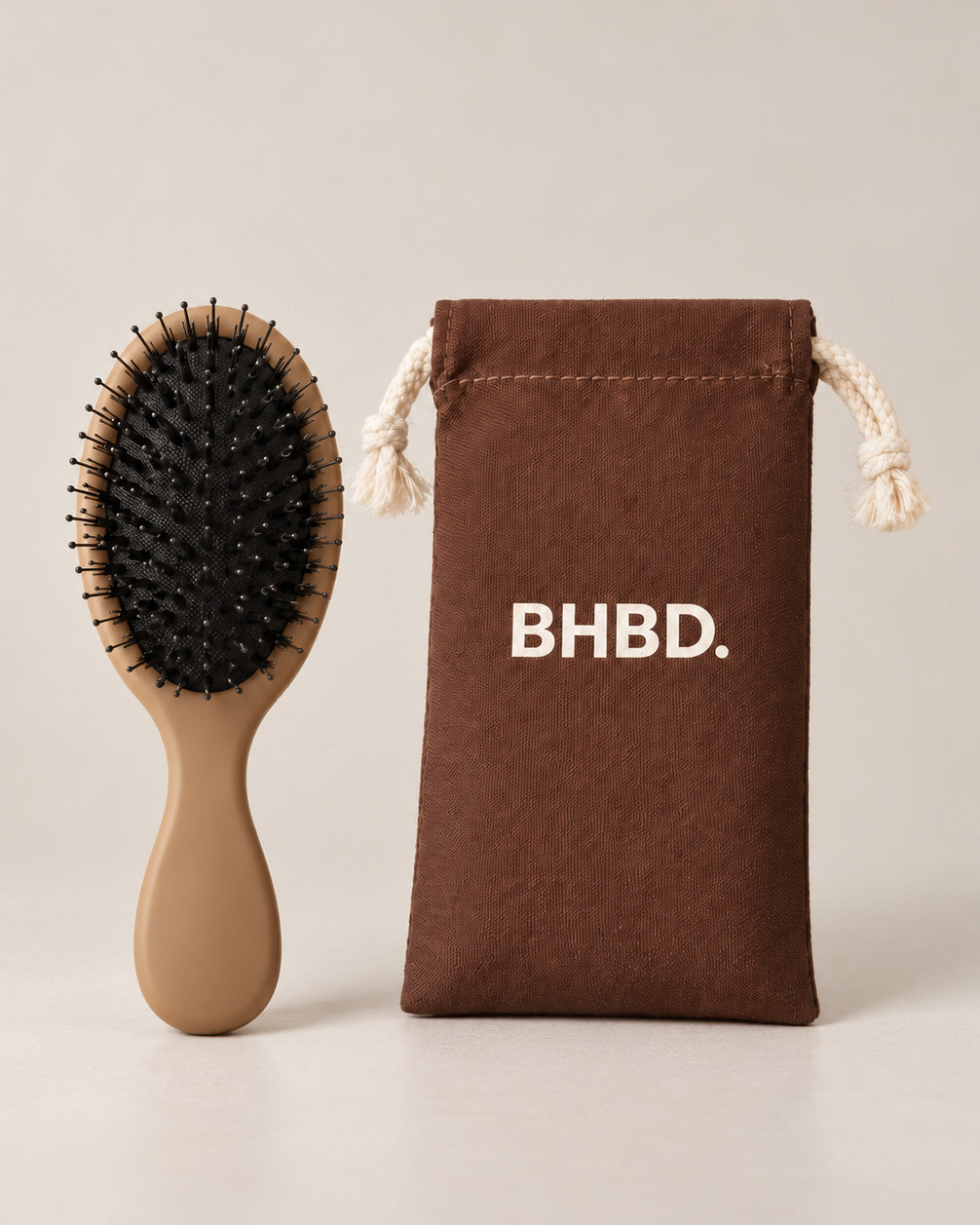 BHBD Mini Paddle Brush – beige paddle hairbrush with natural boar and nylon bristles that smooths and detangles hair, shown next to its brown bag