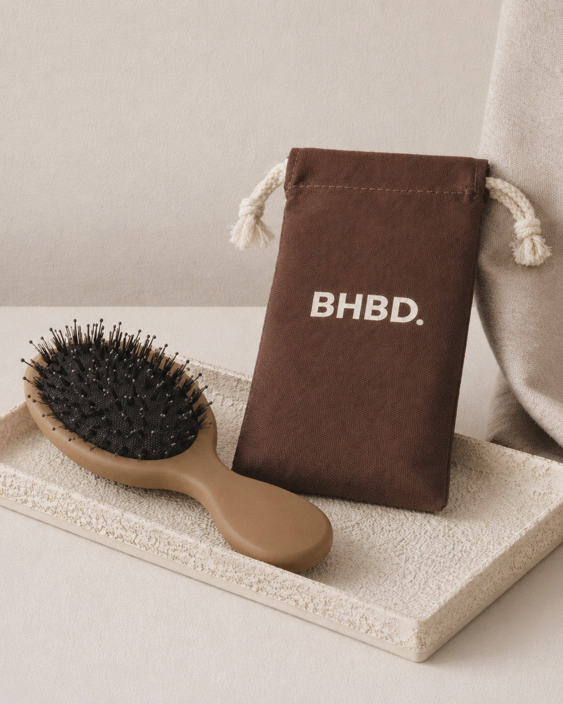 BHBD Mini Paddle Brush – beige paddle hairbrush with natural boar and nylon bristles that smooths and detangles hair, shown next to its brown bag