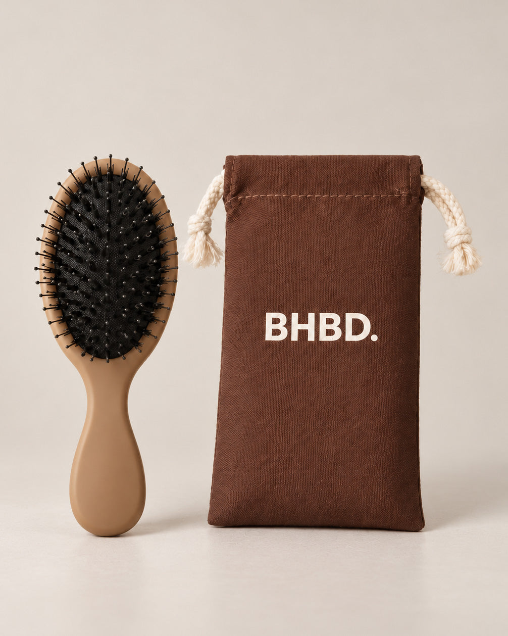 BHBD Mini Paddle Brush – beige paddle hairbrush with natural boar and nylon bristles that smooths and detangles hair, shown next to its brown bag
