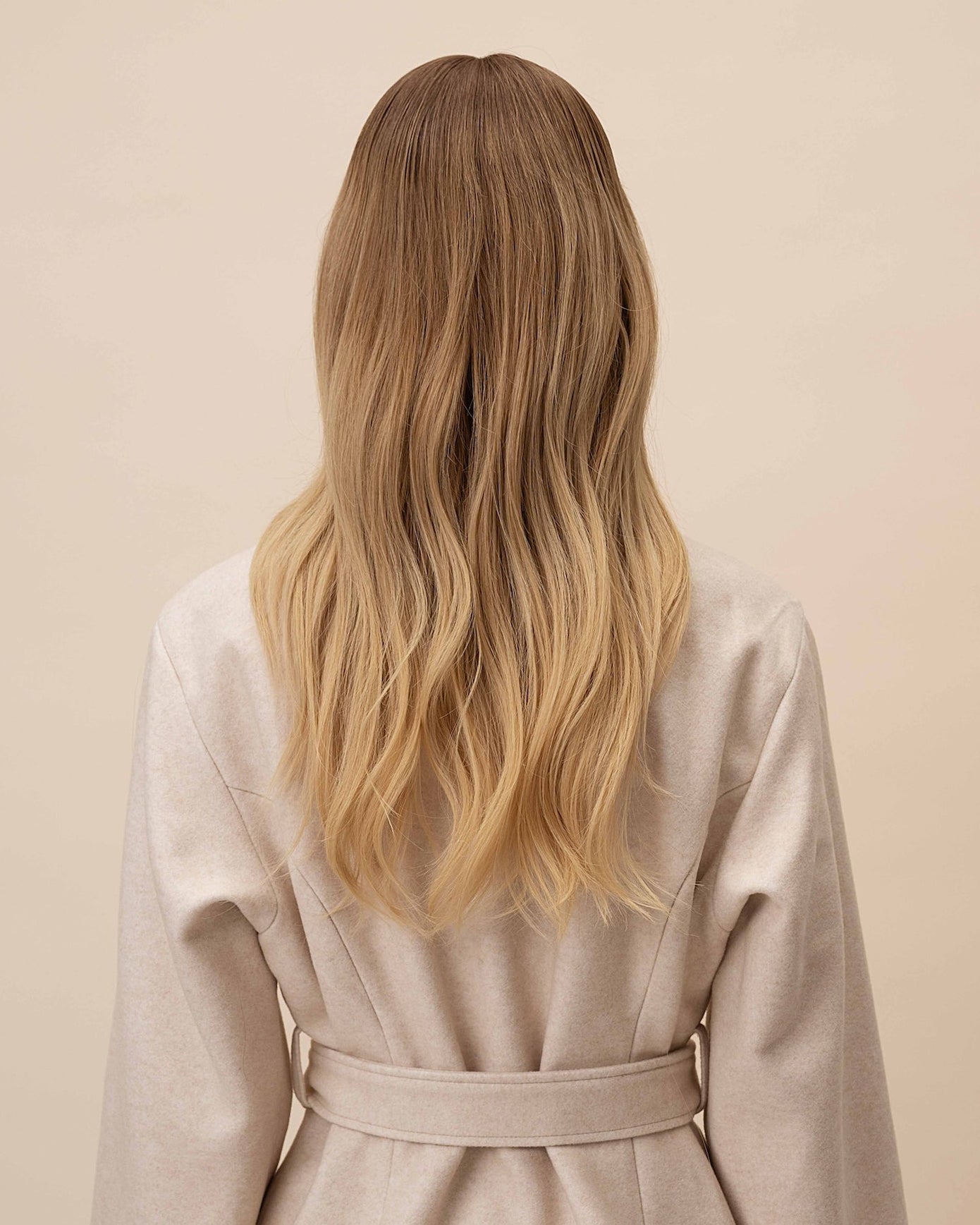 Statice Wig 40 cm medium blonde human hair with softly layered lengths and natural darker root, shown from the back on model to highlight the smooth cut