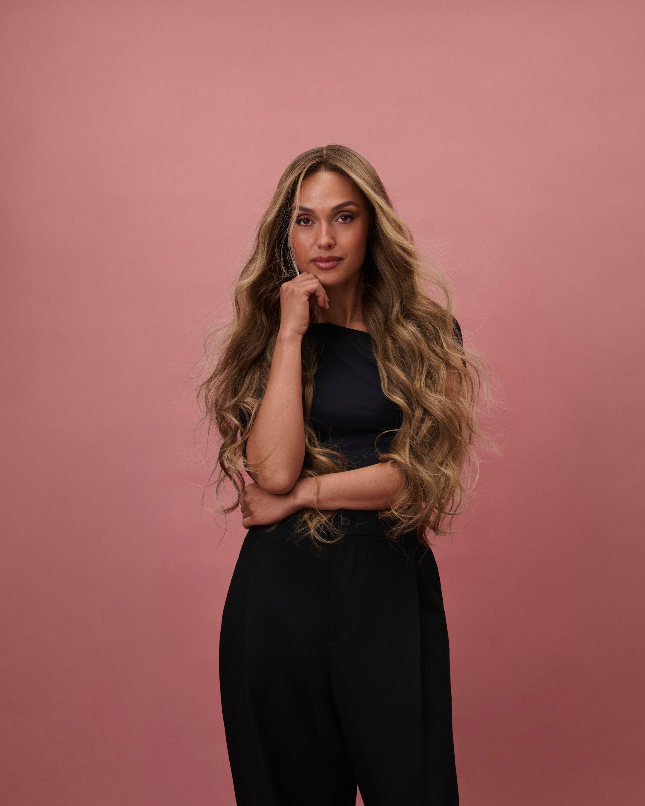 Noble Nightshade Wig 65 cm – dark blonde rooted Remy human hair wig with softly layered 65 cm lengths and money‑piece highlights on HD lace, shown on a model in a black outfit against a pink background