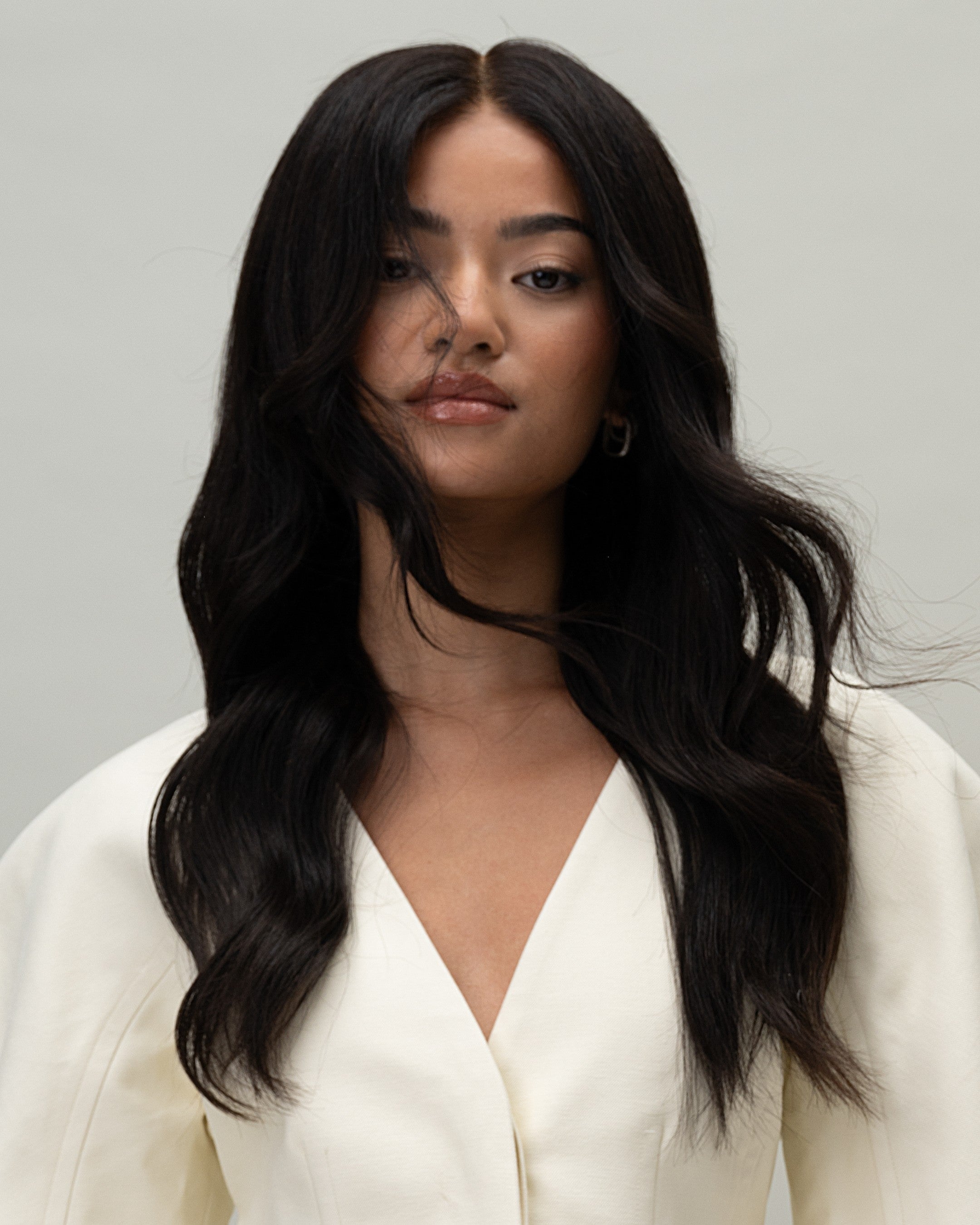 Model wearing wig. front view, white outfit. Aurora Wig – 40cm full lace wig in deep natural black; 100% Remy hair with pre-plucked hairline and HD lace; styled with soft layers.