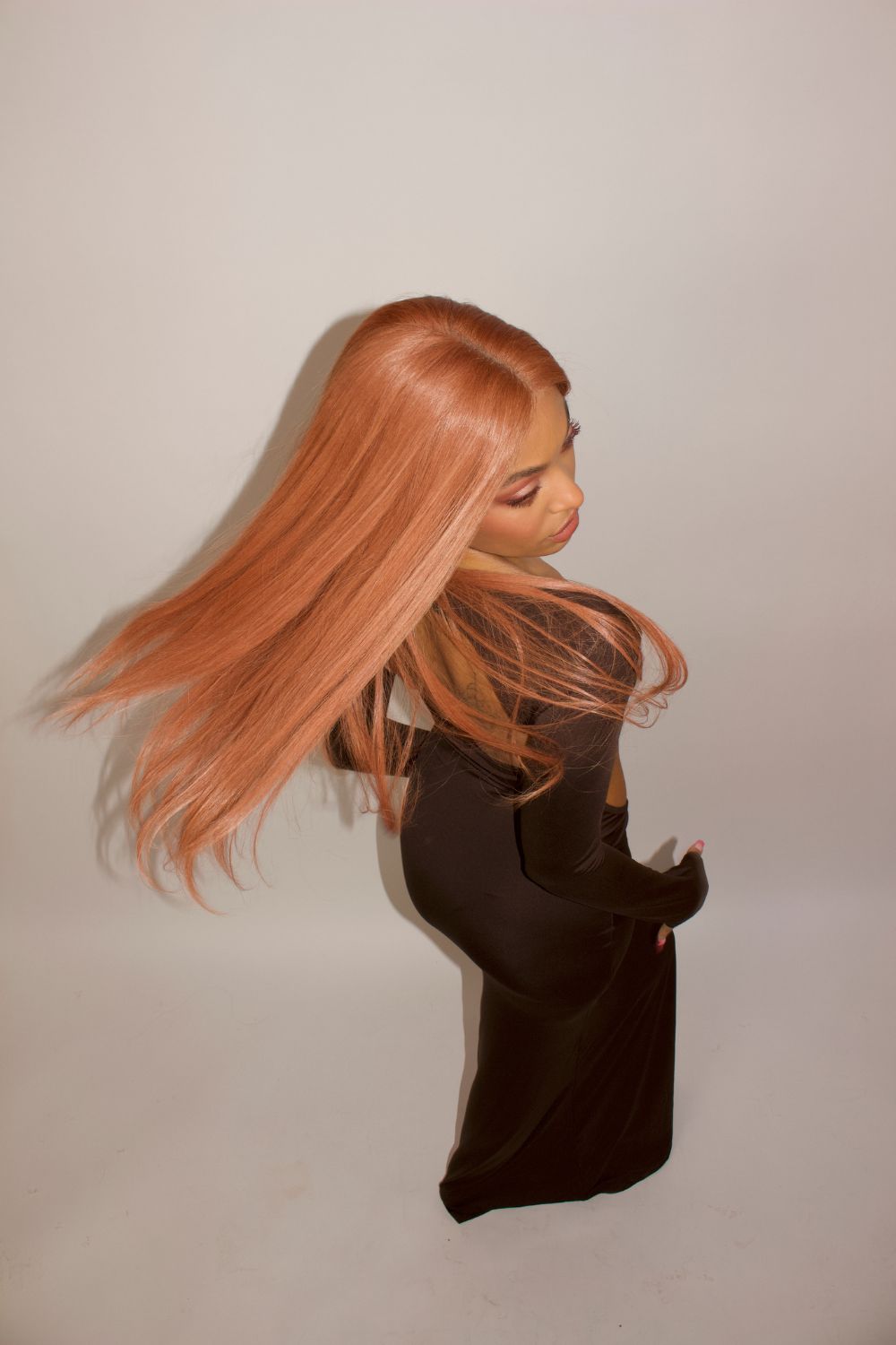 En modell bär BHBD Electric wig i 50cm. Peruken är i en livlig persika tonad kopparfärg. 