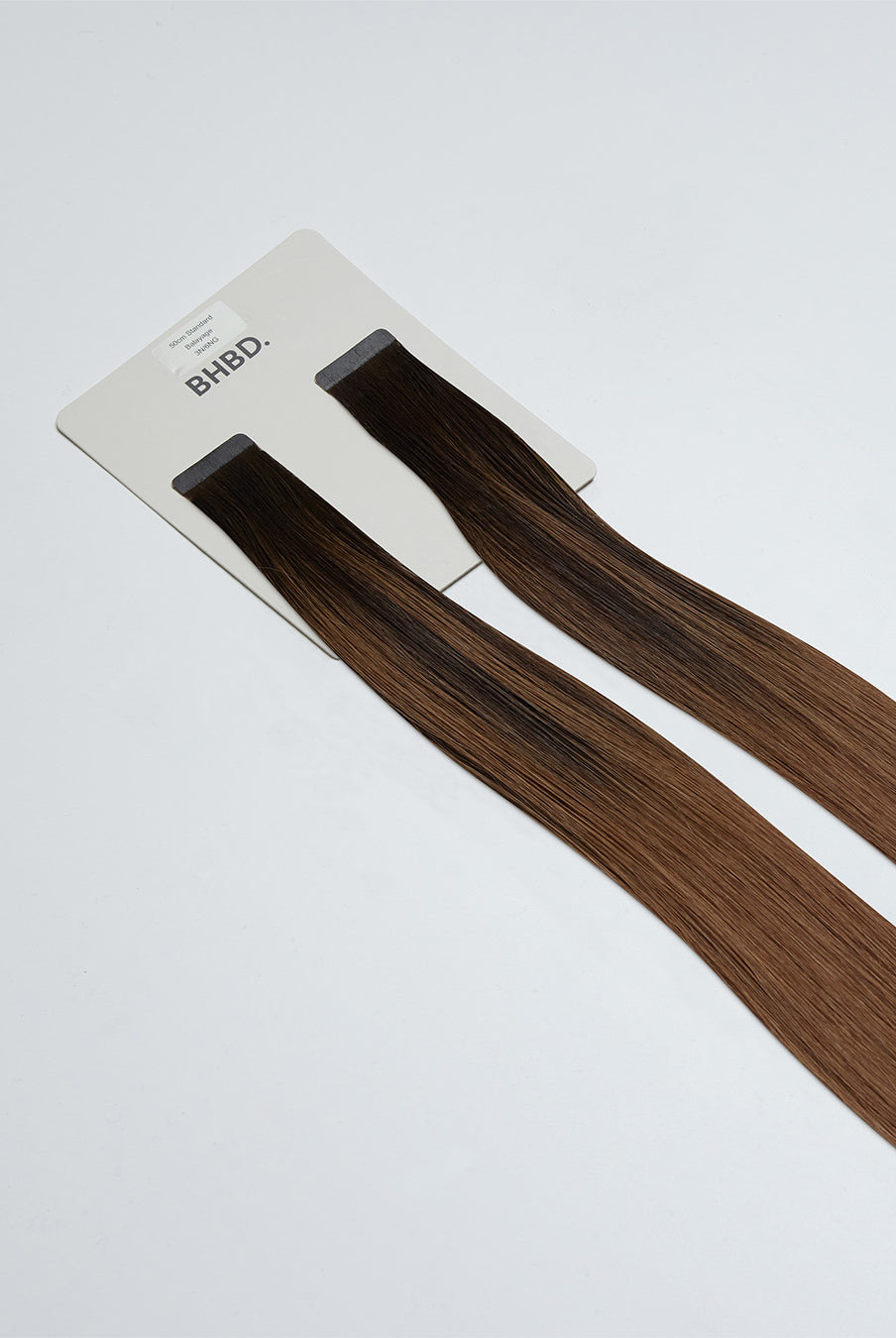 Tape Extensions 3N/6NG – pre-taped Remy human hair extensions in deep natural brown and neutral golden brown blend; seamless, soft and tangle-free; comes in 35cm, 50cm, and 60cm. 100% Remy hair, gentle extensions.