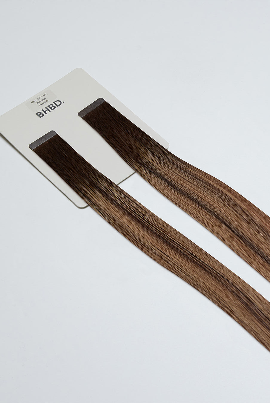Tape Extensions 4NA/8NG – pre-taped Remy human hair extensions in natural ash brown blended with golden blonde; seamless, soft and tangle-free; comes in 35cm, 50cm, and 60cm. 100% Remy hair, gentle extensions.