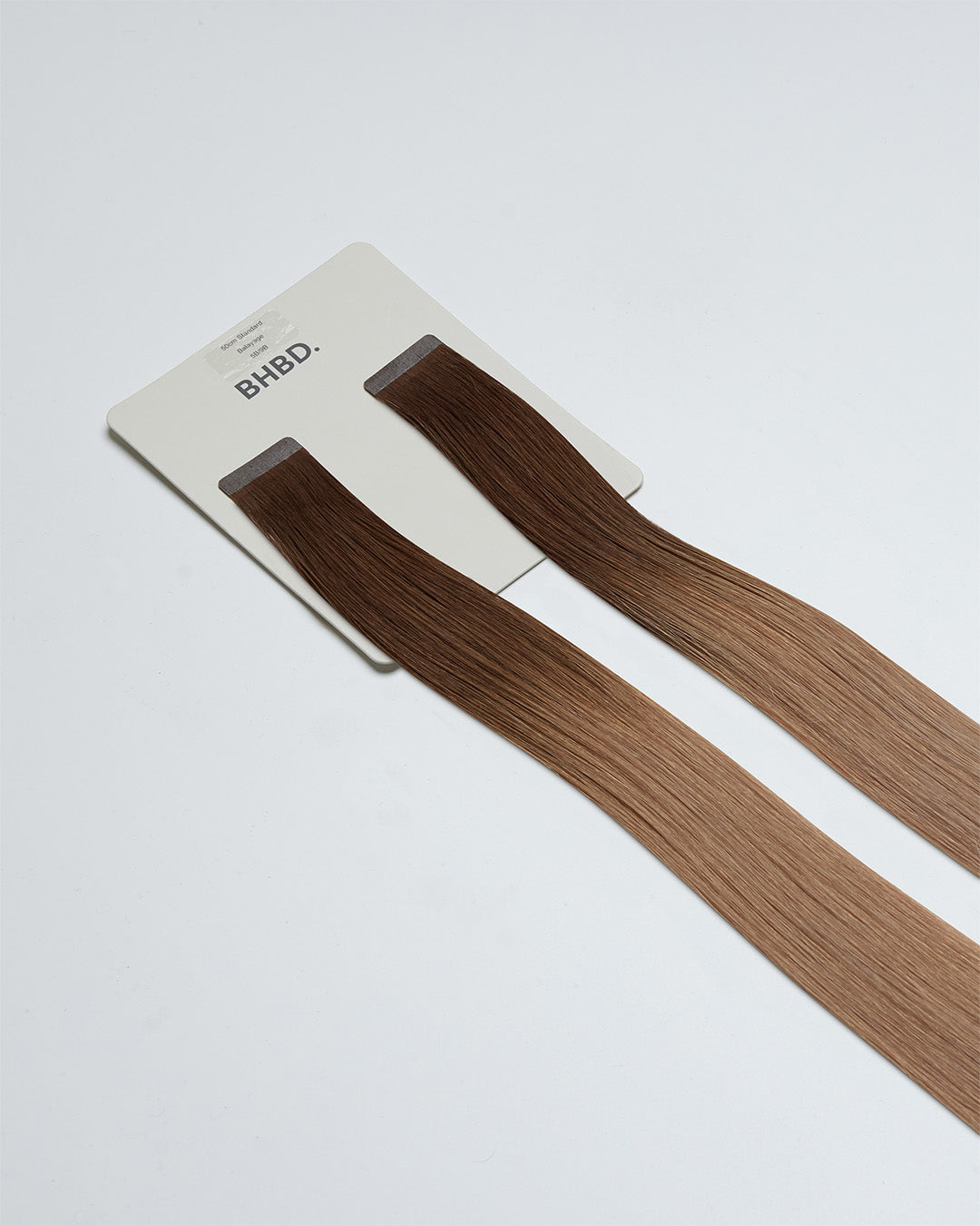 Tape Extensions 5B/9B – pre-taped Remy human hair extensions in medium brown blended with light beige blonde; seamless, soft and tangle-free; comes in 35cm, 50cm, and 60cm. 100% Remy hair, gentle extensions.