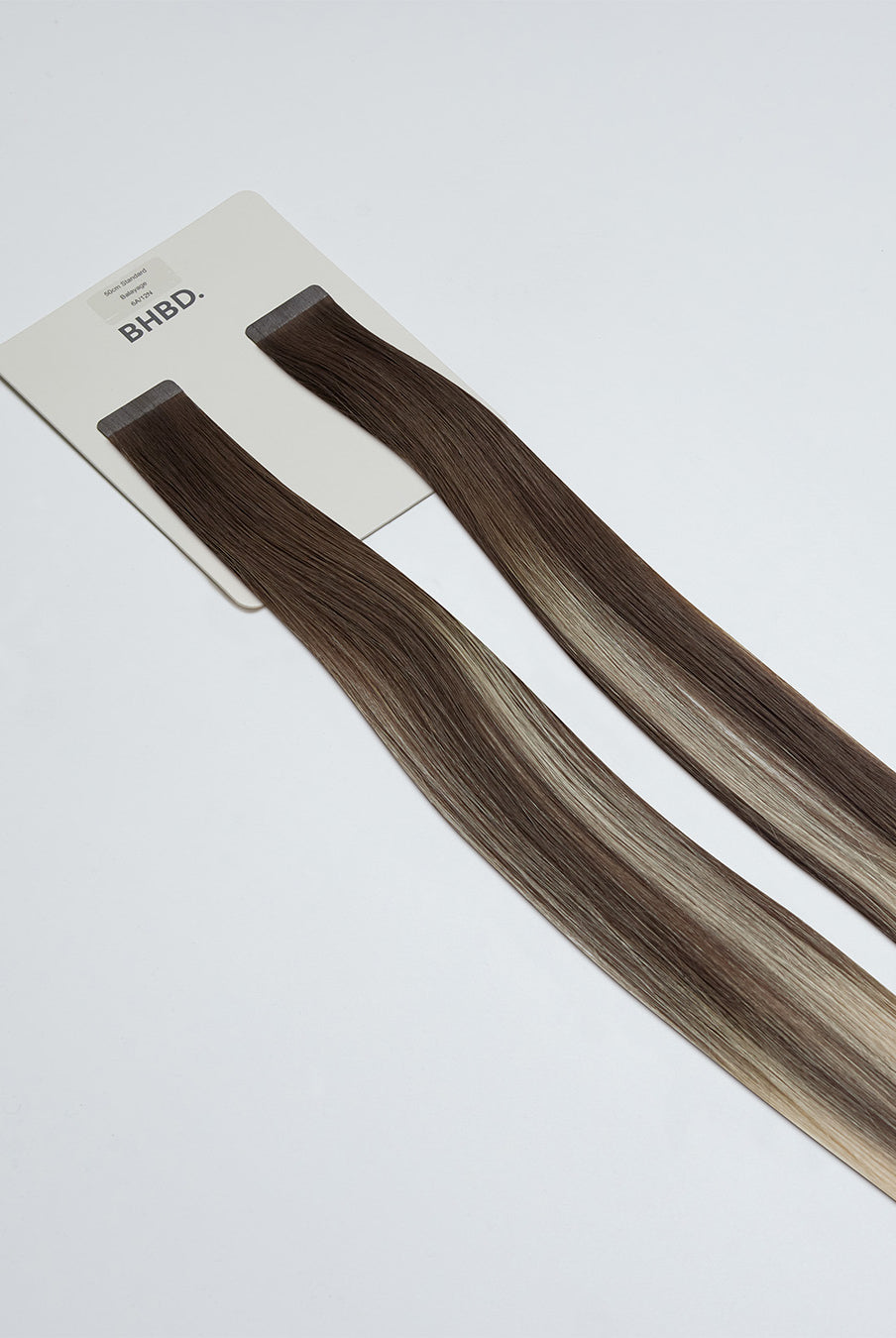 Tape Extensions 6A/12N – pre-taped Remy human hair extensions in medium ash brown blended with light natural blonde; seamless, soft and tangle-free; comes in 35cm, 50cm, and 60cm. 100% Remy hair, gentle extensions.