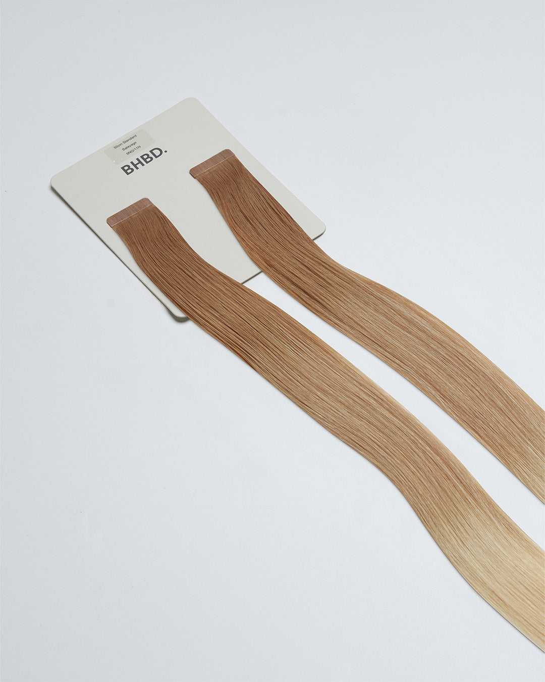 Tape Extensions 9NG/11N – pre-taped Remy human hair extensions in golden natural blonde blended with medium natural blonde; seamless, soft and tangle-free; comes in 35cm, 50cm, and 60cm. 100% Remy hair, gentle extensions.