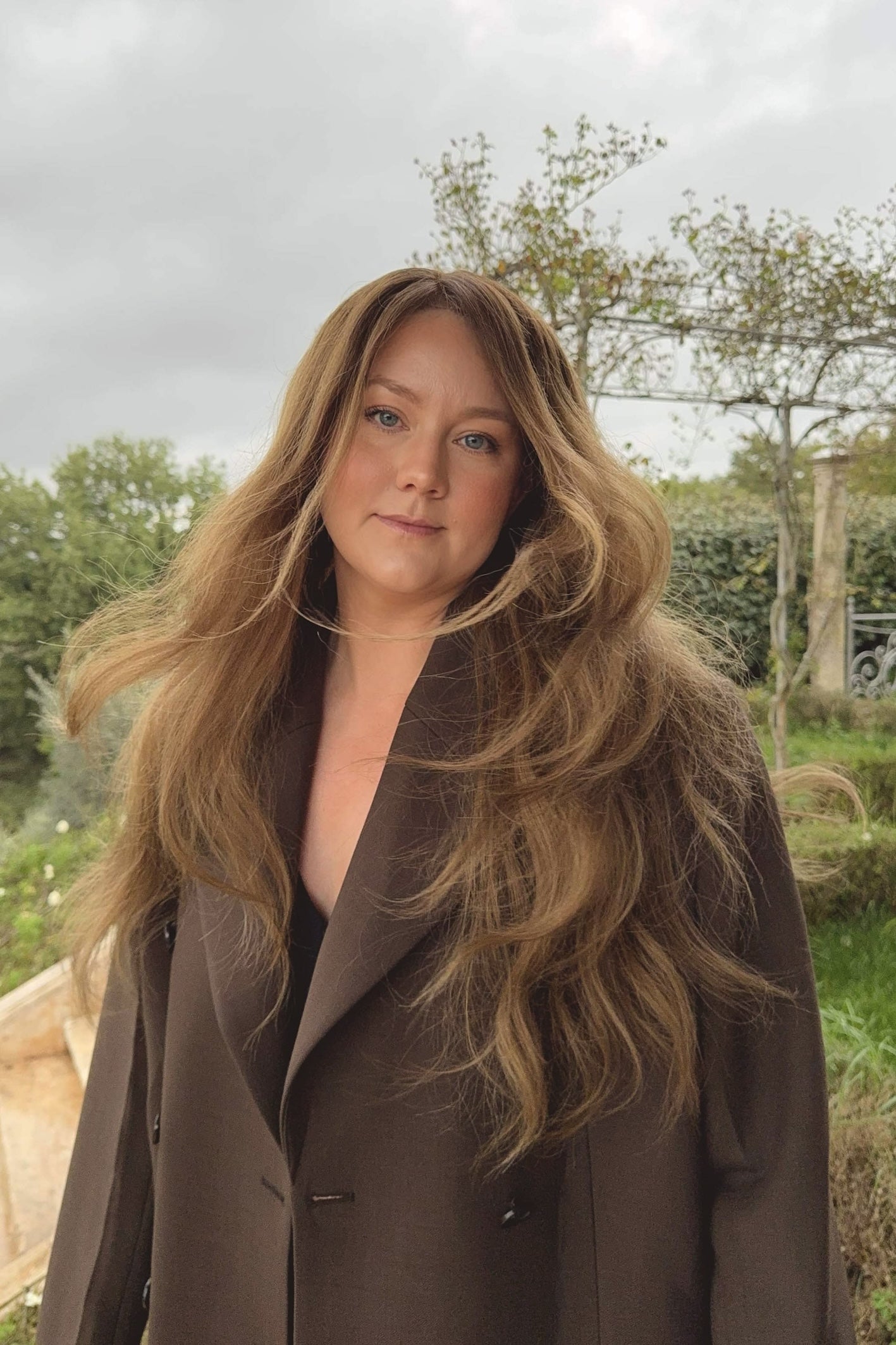 Woman wearing a long BHBD Elena wig with blended balayage, soft caramel brown tones and cool medium brown lengths.