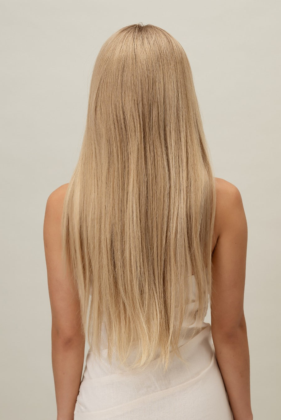 Ash Blonde Wig 40 cm 100% Remy human hair with natural color blend and darker root, softly layered and shown on model in white dress.