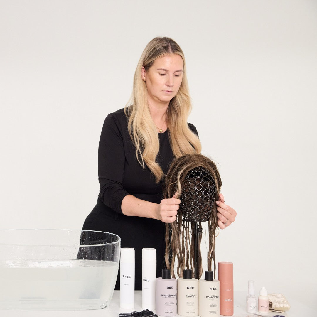 Woman putting a wig on a wig stand for drying
