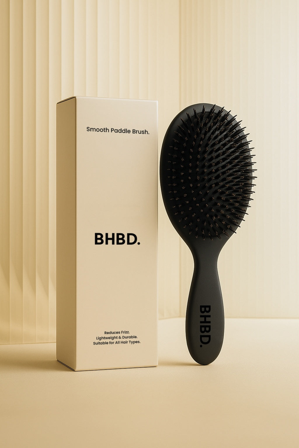 BHBD Paddle Brush – black paddle hairbrush with natural boar and nylon bristles that smooths and detangles hair, shown next to its beige packaging