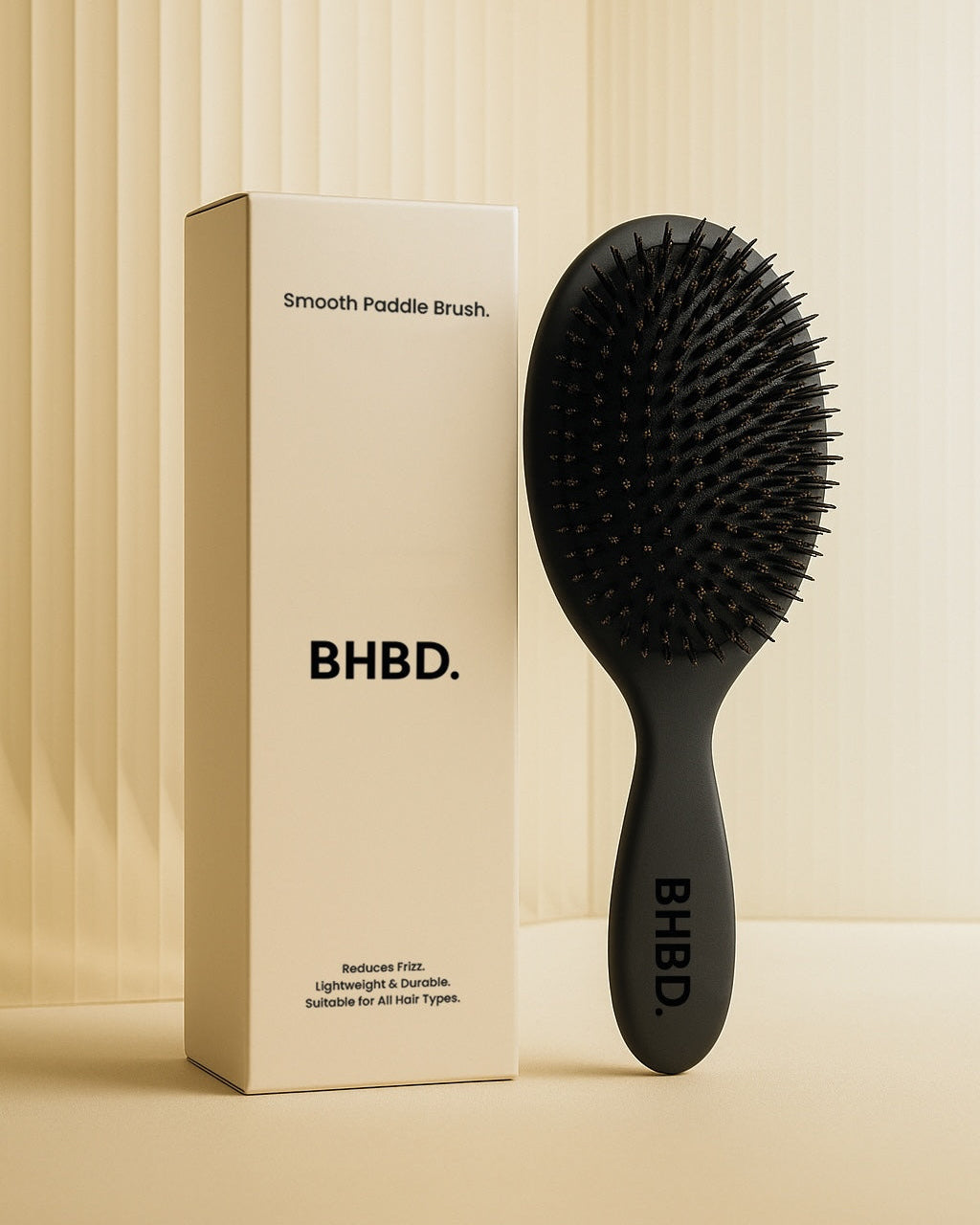 BHBD Paddle Brush – black paddle hairbrush with natural boar and nylon bristles that smooths and detangles hair, shown next to its beige packaging