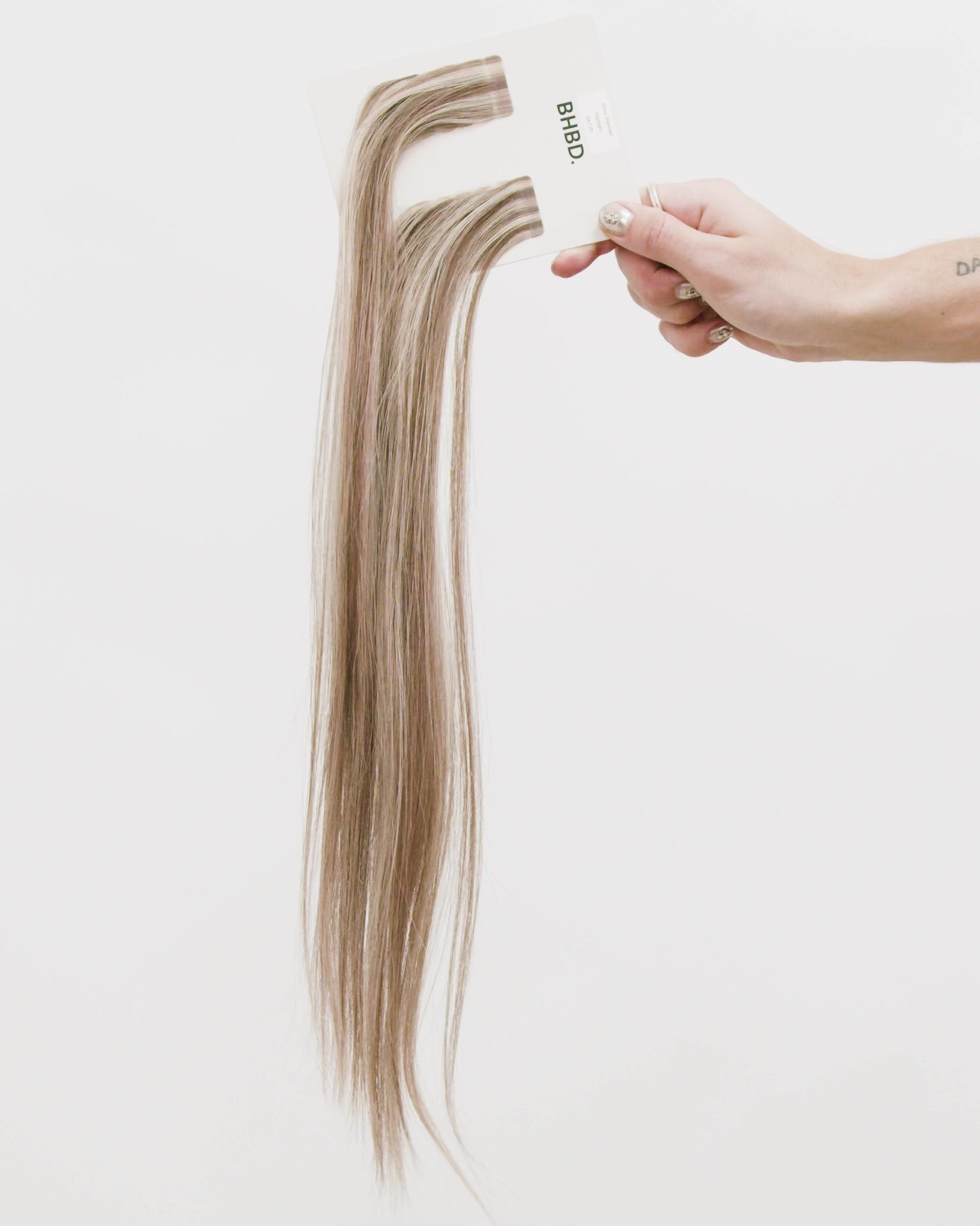 Tape Extensions 8A/12N – pre-taped Remy human hair extensions in medium ash blonde blended with light natural blonde; seamless, soft and tangle-free; comes in 35cm, 50cm, and 60cm. 100% Remy hair, gentle extensions.