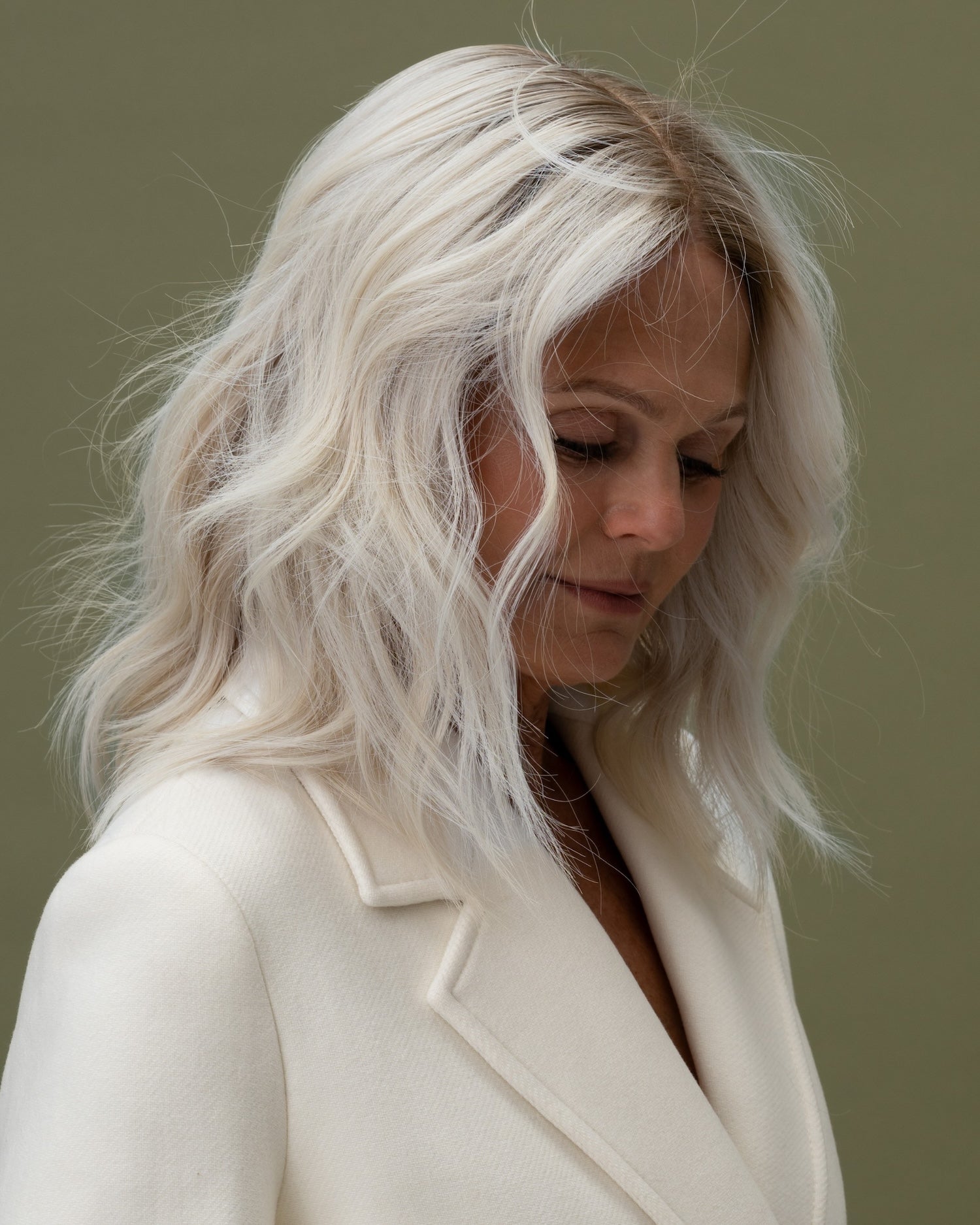 Fiorella Wig 35 cm platinum ash blonde human hair wig with cool dark blonde roots, softly waved and shown on model for a natural look