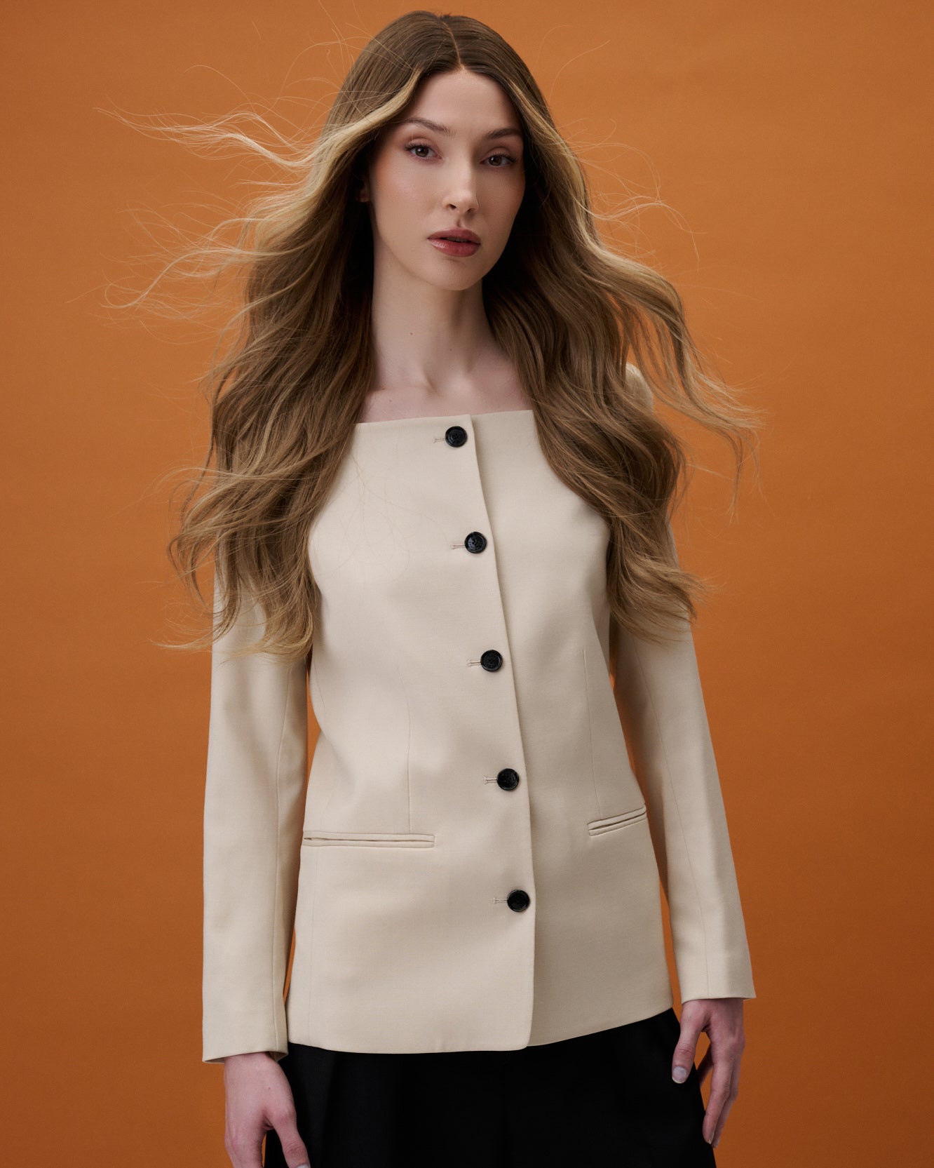 Noble Nightshade Wig 50 cm long layered human hair in natural dark blonde blend, hand-tied on transparent HD lace for realistic scalp and parting on model with wind blowing.