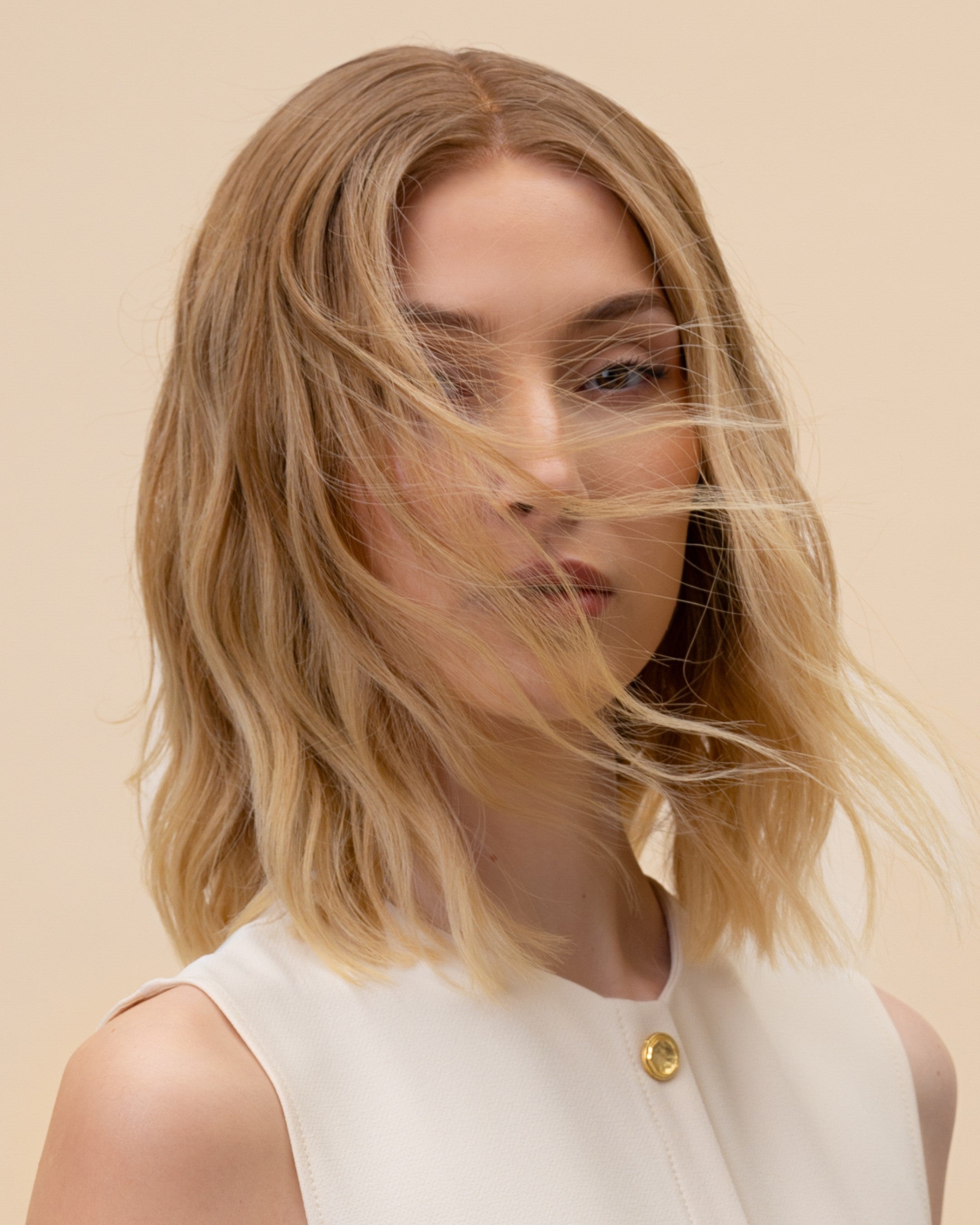 Statice Wig 30 cm medium blonde human hair wig with natural golden tones and darker root, neatly cut for a modern, elegant look, shown on model.