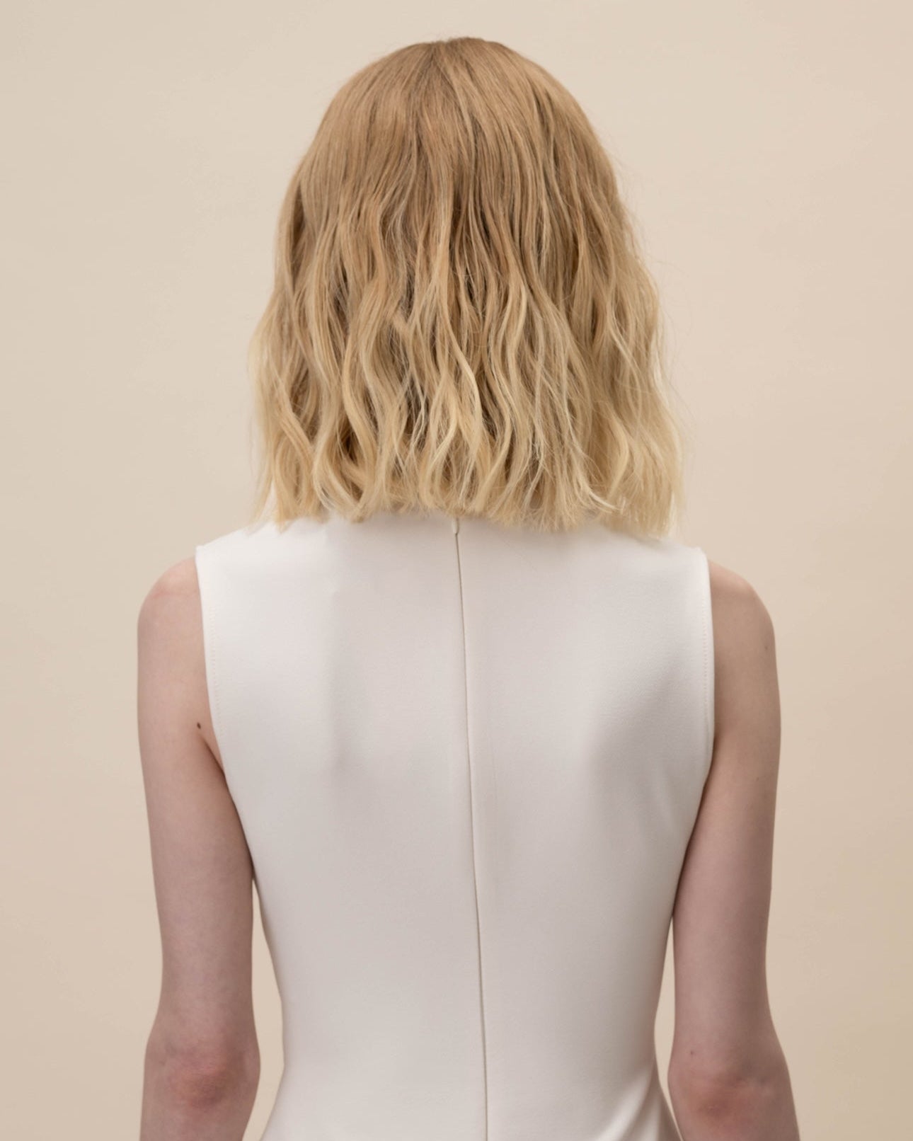 Statice Wig 30 cm Remy human hair wig in medium blonde with soft golden tones and natural darker root, shown from the back on model.