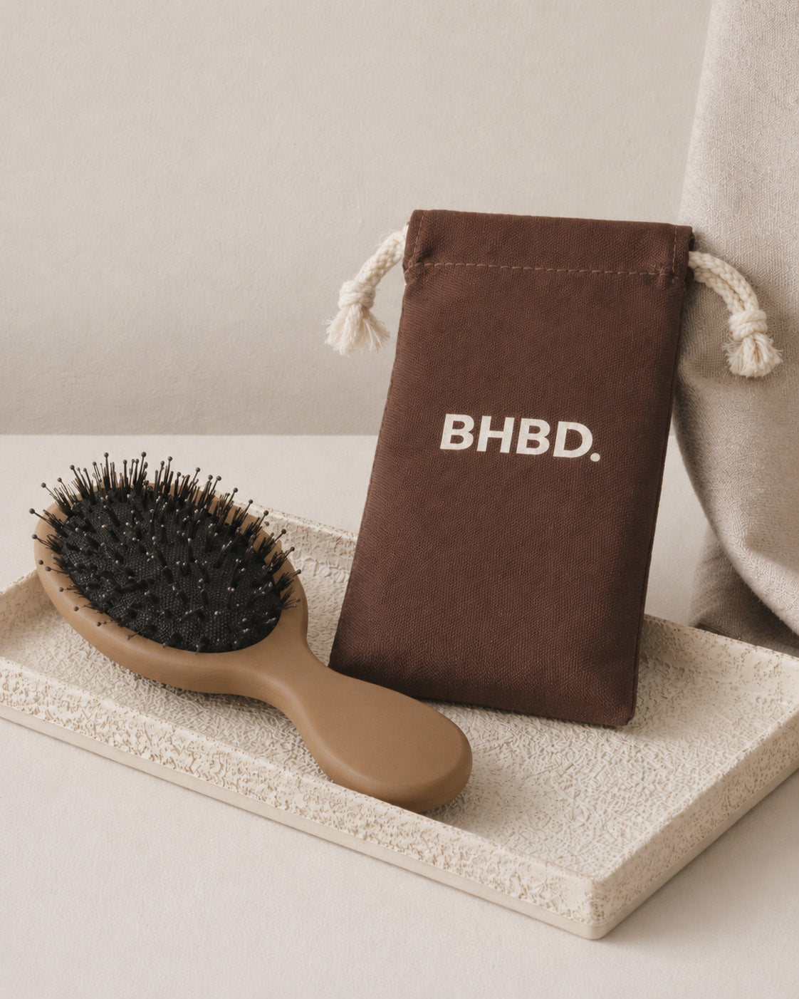 BHBD Mini Paddle Brush – beige paddle hairbrush with natural boar and nylon bristles that smooths and detangles hair, shown next to its brown bag