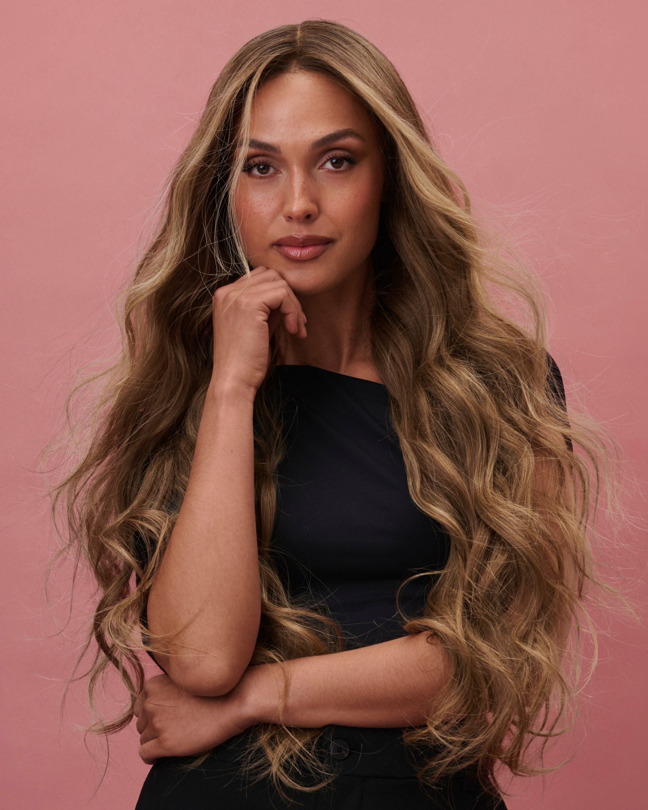 Noble Nightshade Wig 65 cm – dark blonde rooted Remy human hair wig with softly layered 65 cm lengths and money‑piece highlights on HD lace, shown on a model in a black outfit against a pink background