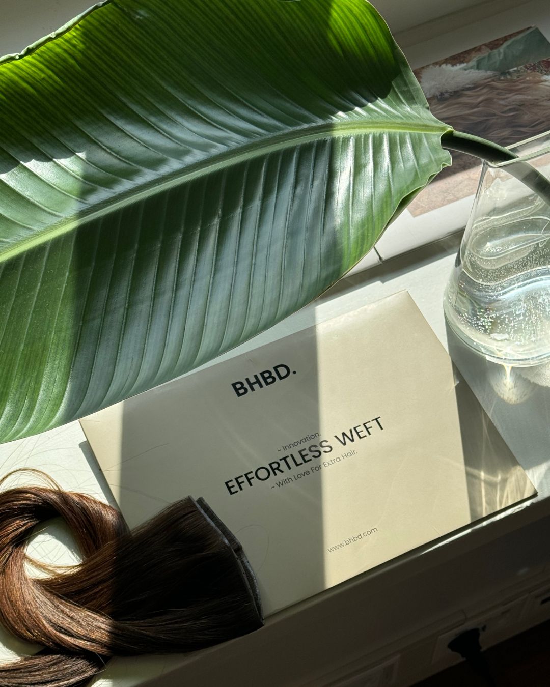 BHBD Weft packaging displayed on a table with natural light and green leaves. 100% Remy hair, gentle extensions.