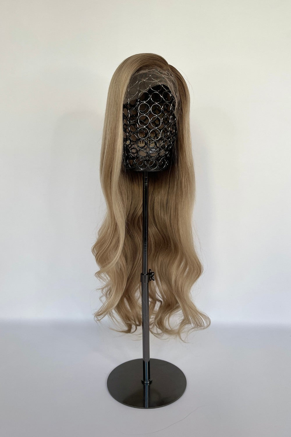 Premium BHBD half or full lace wig in a sandy blonde shade with long, soft waves cascading down. Displayed on a mannequin stand, made with 100% real Remy hair for a natural parting and seamless, elegant finish.