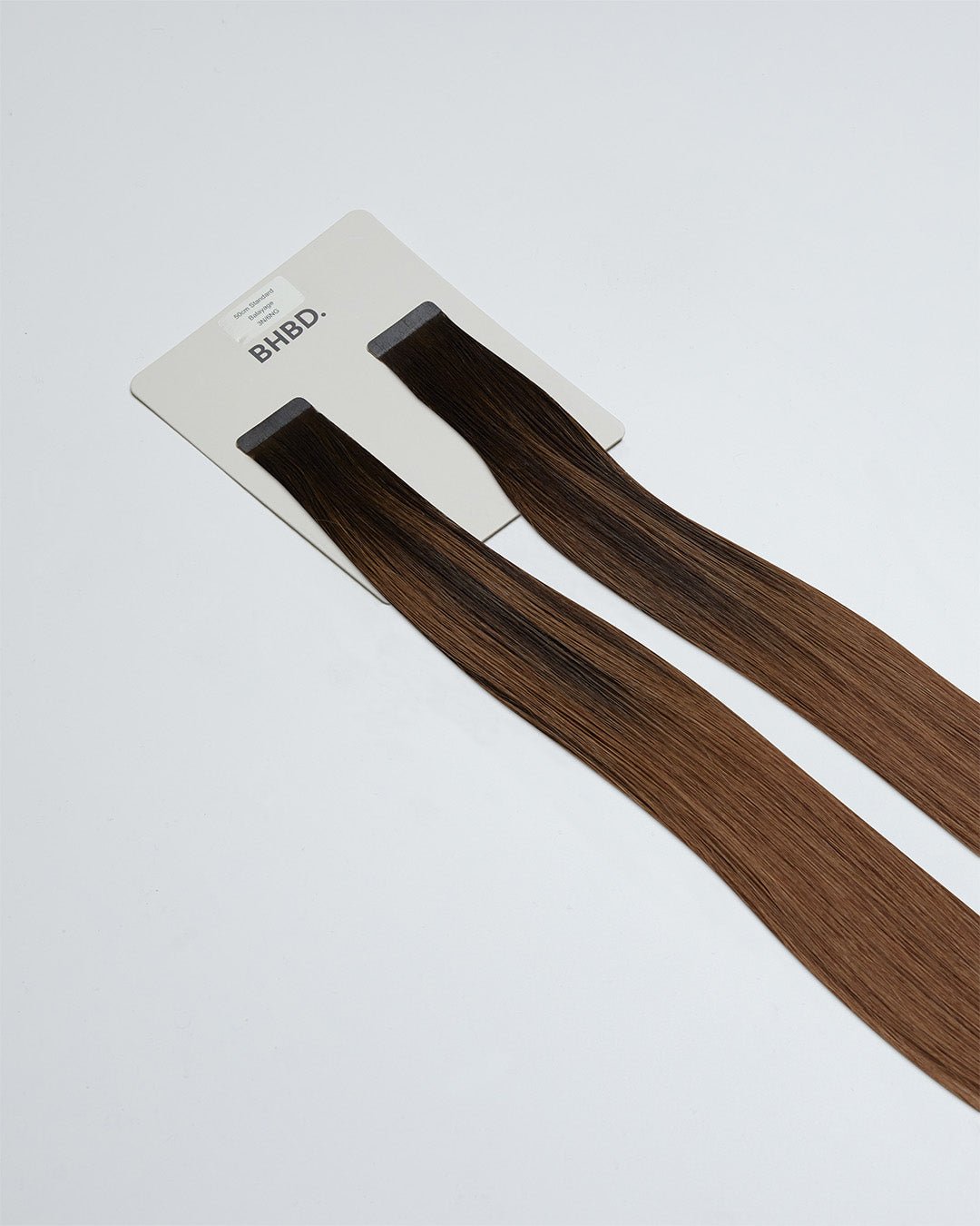 Tape Extensions 3N/6NG – pre-taped Remy human hair extensions in deep natural brown and neutral golden brown blend; seamless, soft and tangle-free; comes in 35cm, 50cm, and 60cm. 100% Remy hair, gentle extensions.