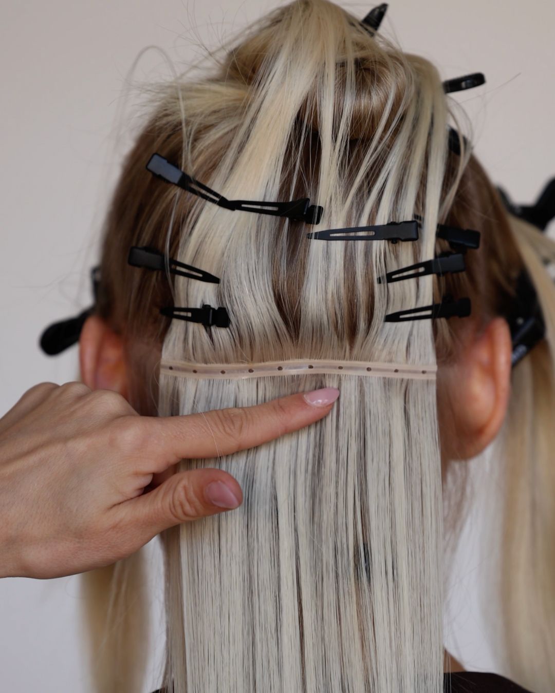 Stylist sectioning blonde hair and preparing to attach BHBD Weft extensions with micro rings. 100% Remy hair, gentle extensions.