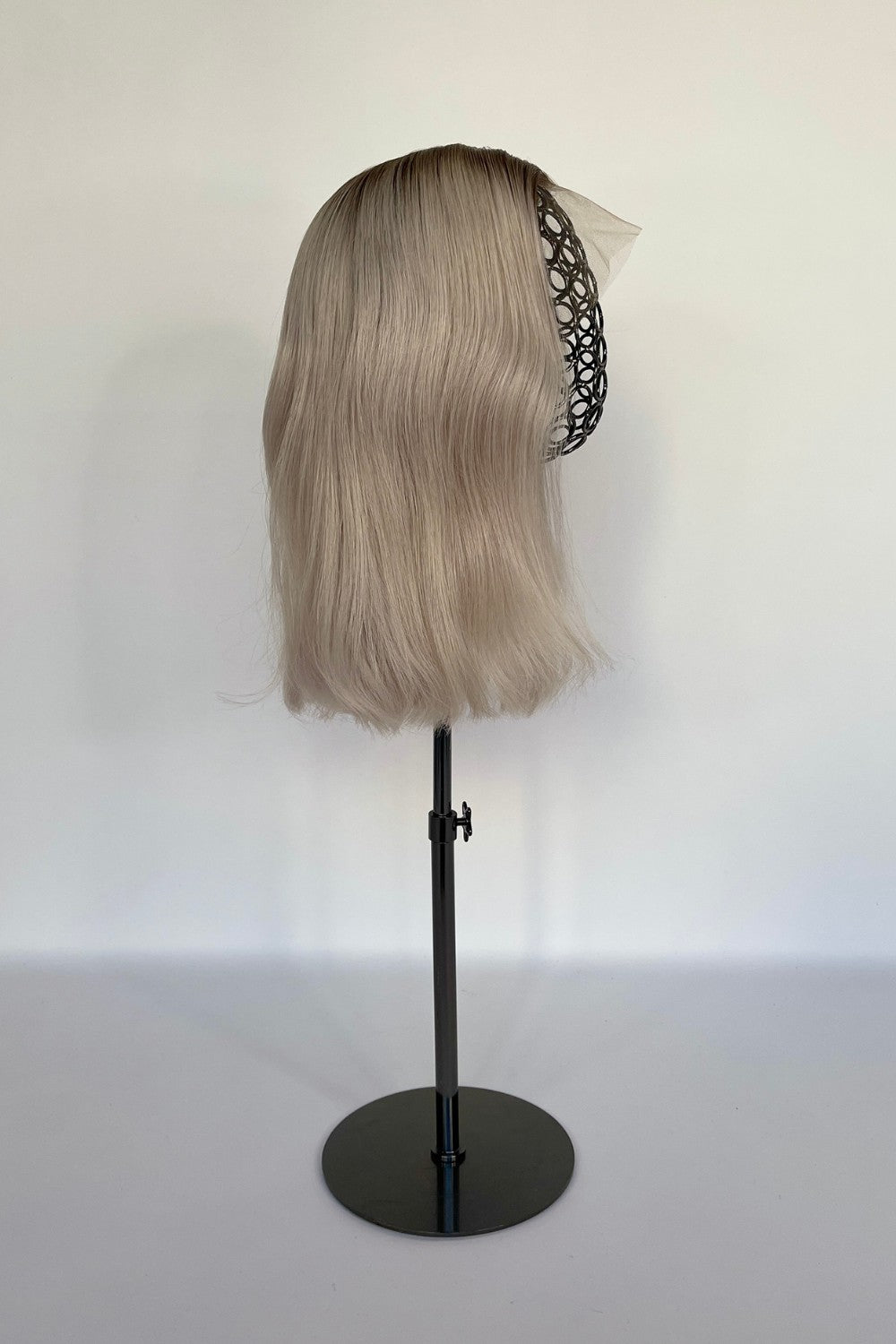 BHBD premium half or full lace wig in an ash blonde shade with darker blond roots and soft, smooth waves, displayed on a mannequin stand. Made with 100% real Remy hair, featuring a natural parting and seamless finish for an elegant and realistic look.