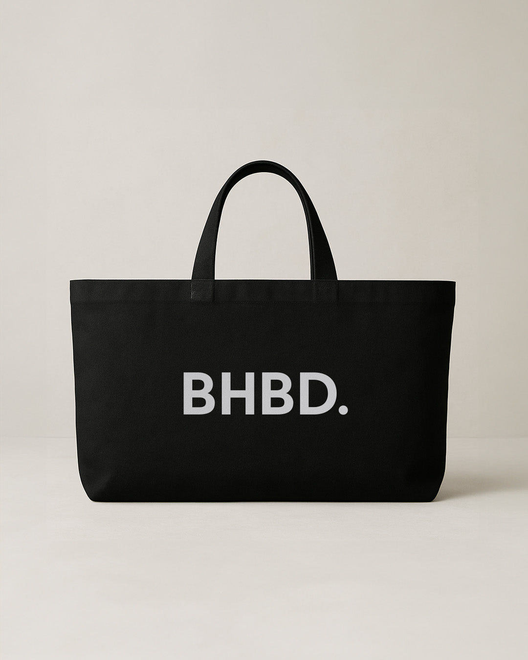 BHBD Tote Bag – black cotton tote bag with white BHBD logo on a beige background, durable and lightweight for everyday essentials