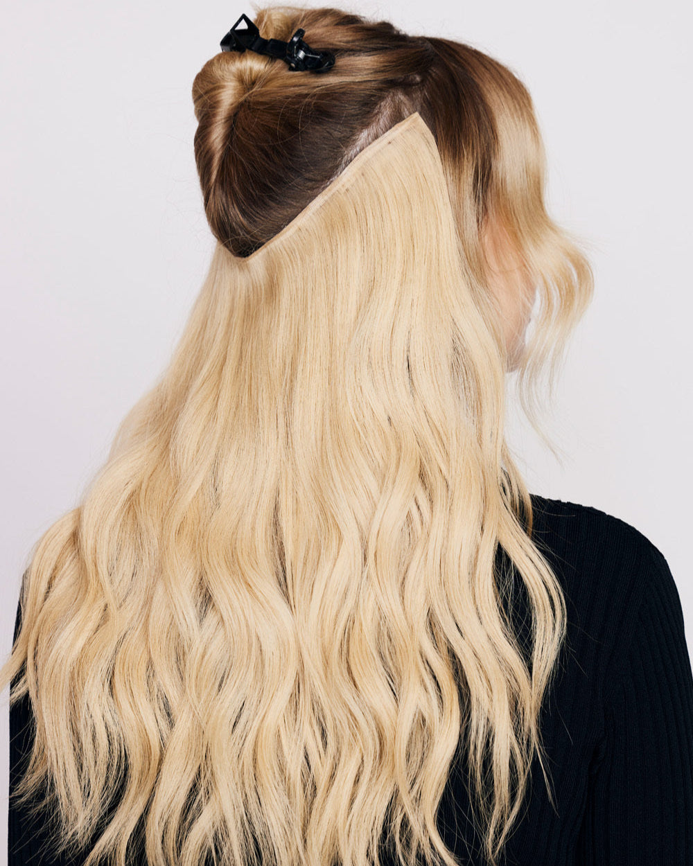 Person with hair parting that shows where to apply BHBD Halo blonde extensions.