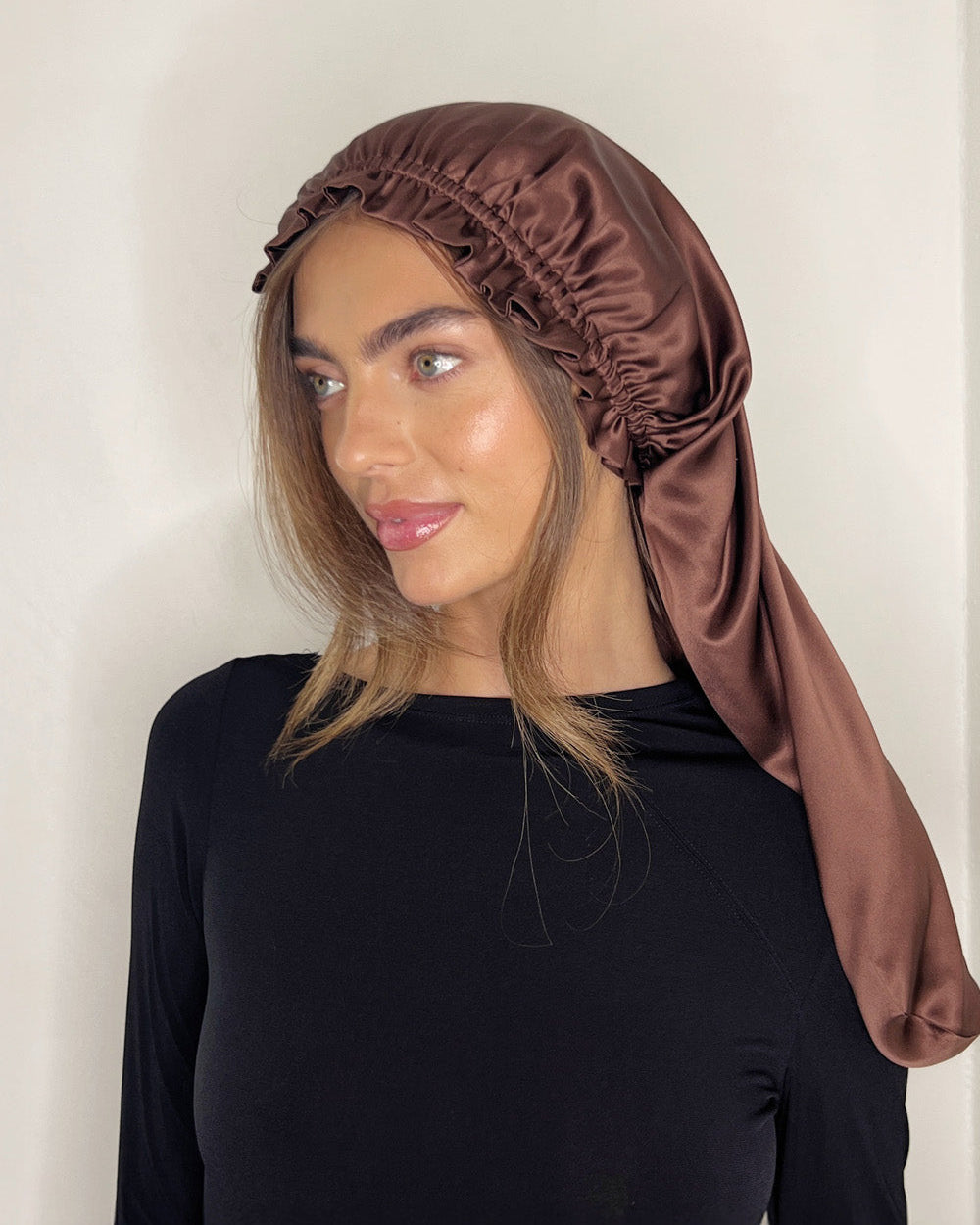 Model wearing BHBD Silk Bonnet in chocolate brown, made from 100% mulberry silk; double-layered design for smooth overnight protection.