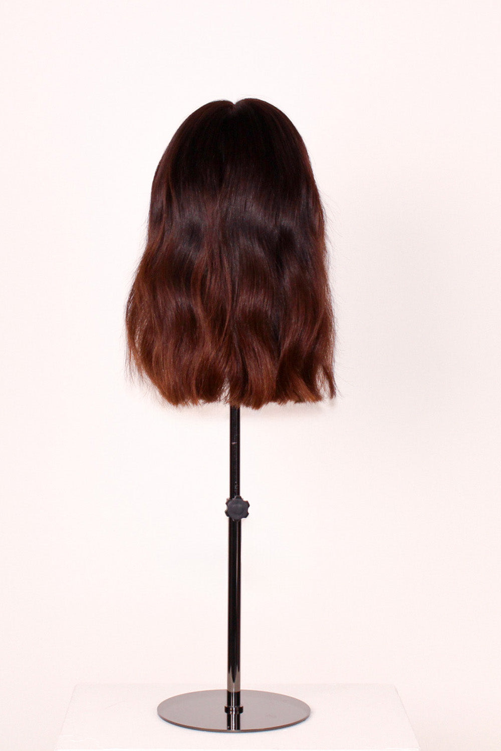 Celosia is a dark brown wig with a length of 30 cm from the back on a wig stand.
