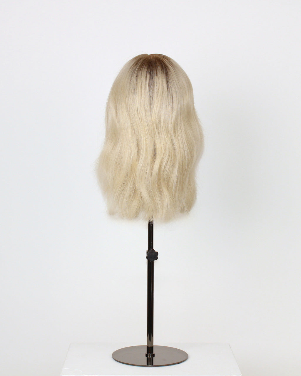 Fiorella Wig 35 cm hand-tied platinum ash blonde human hair wig with cool dark blonde root, displayed on stand with HD lace front. Back view