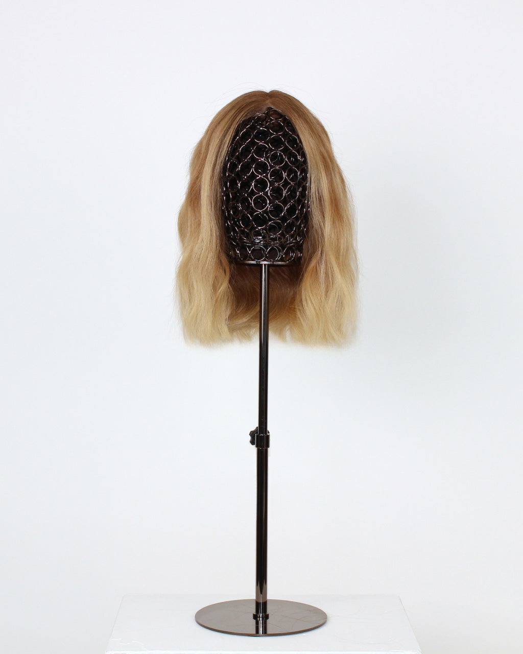 Statice Wig 30 cm human hair wig with darker root and golden blonde tones, hand-tied on HD lace front for realistic scalp effect, displayed on stand. Front view