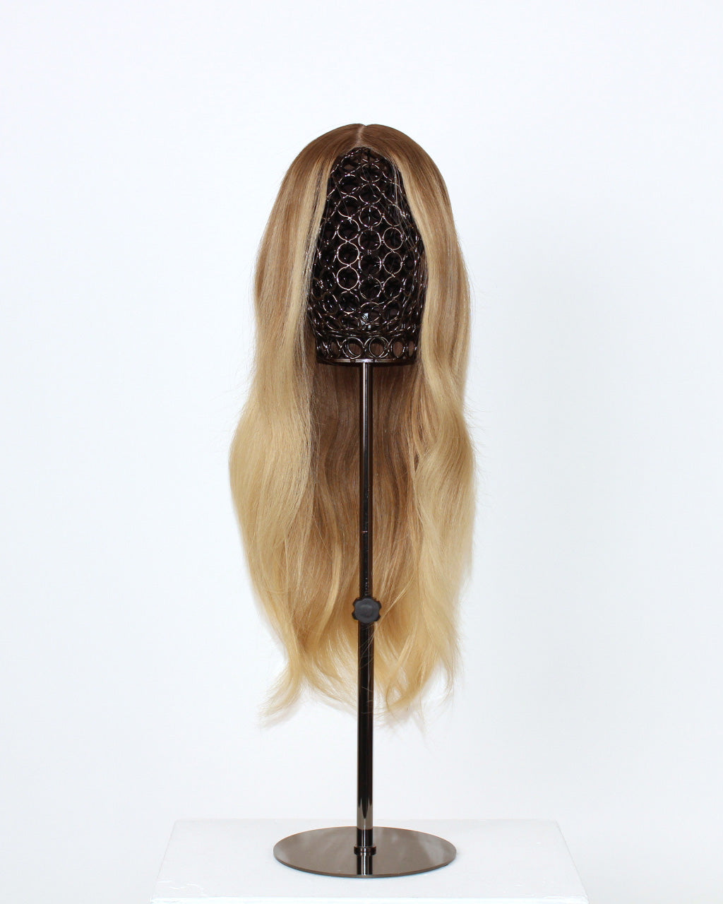 Statice Wig 40 cm medium blonde with darker root and money-piece highlights, hand-tied on transparent HD lace for natural scalp effect, displayed on a wig stand.