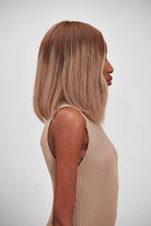 Woman wearing a BHBD Sophia wig. Cool brown wig with pink undertones and lighter highlights in the front.