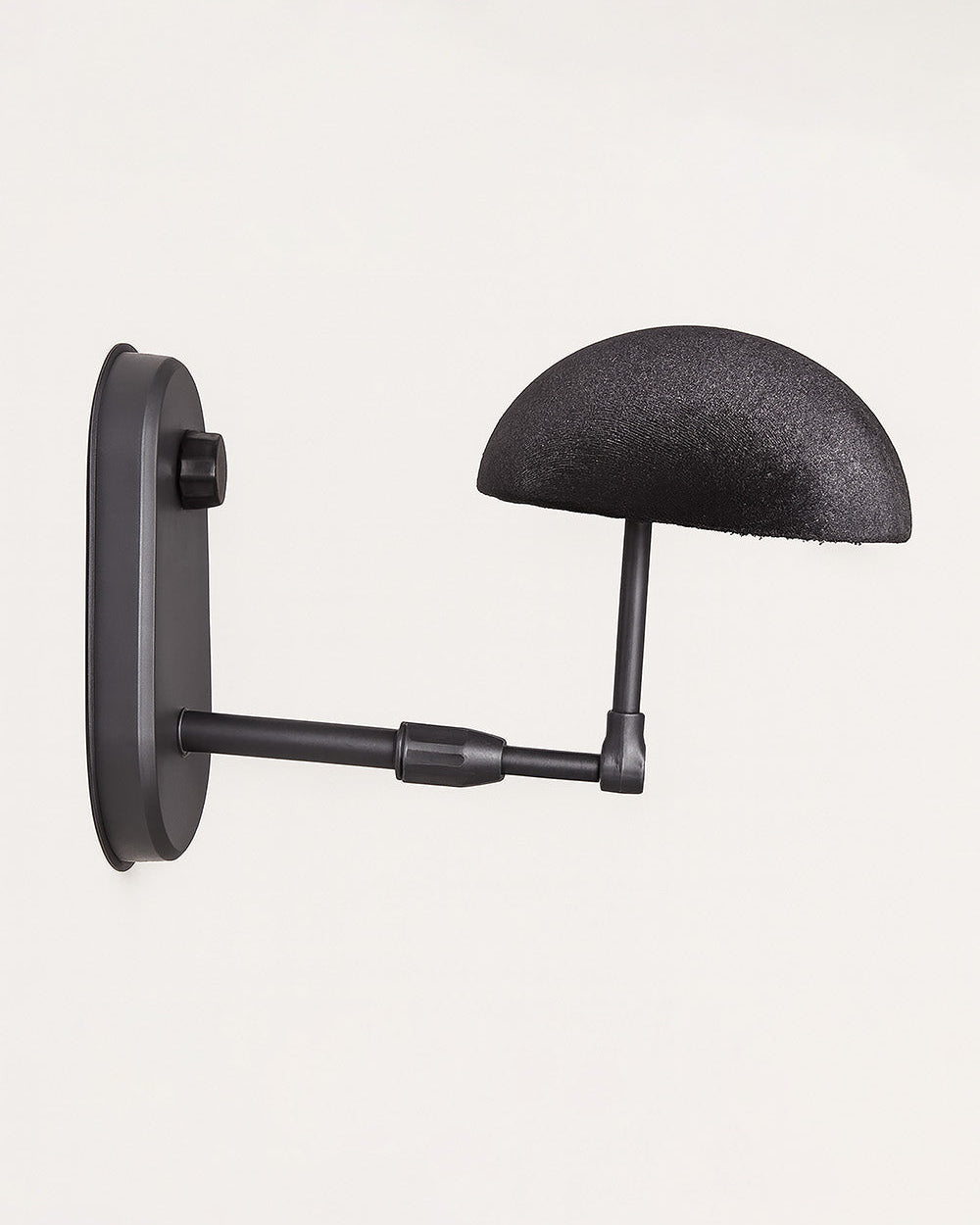 Black wall-mounted travel wig stand with a curved arm.