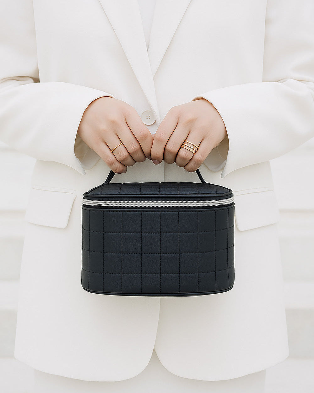 Person holding a black quilted travel wig stand bag