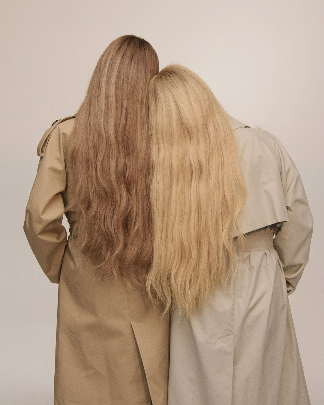 Två kvinnor bakifrån med långt vågigt hår i brunt och blont